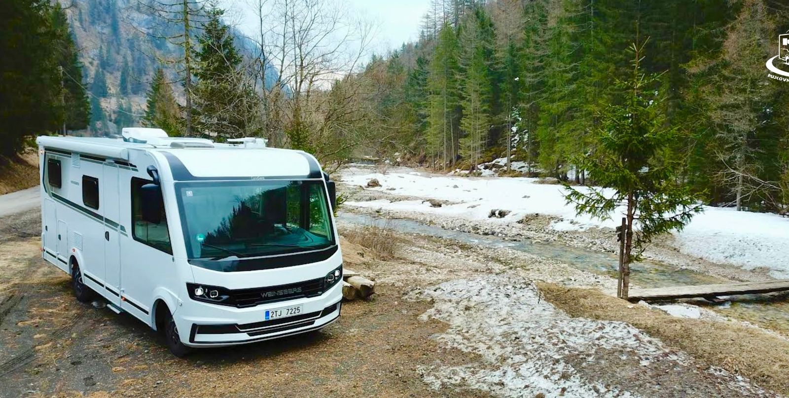 Obytný vůz Weinsberg CaraCore na horách u potoka se sněhem